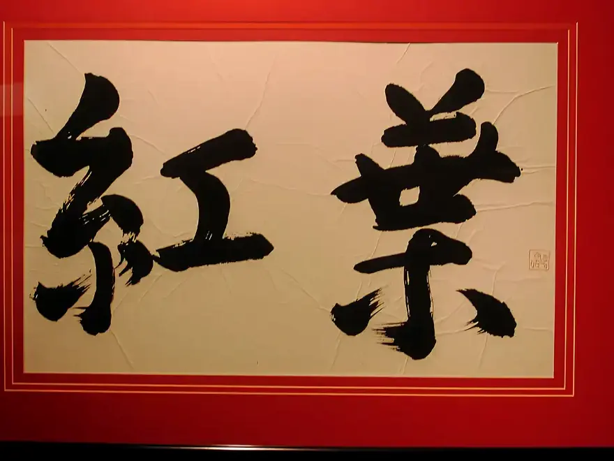 The characters 紅葉, kōyō, brushed in black ink and framed in red on the restaurant wall