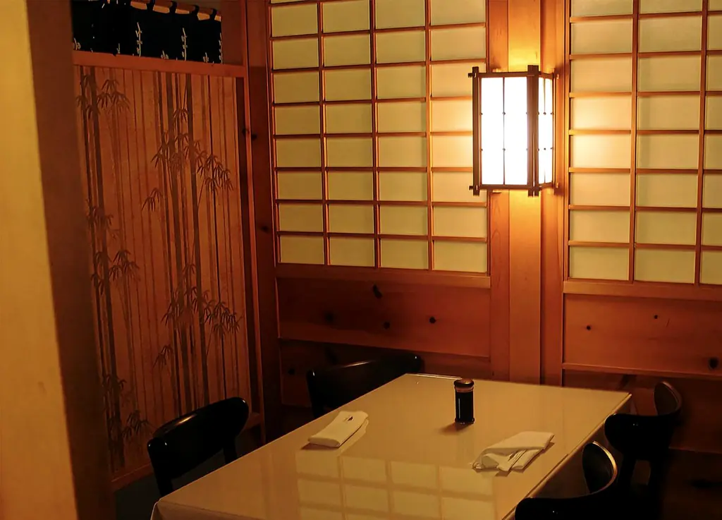 A small dining room with a lantern sconce, shoji walls and a screen printed with bamboo